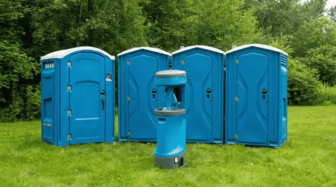 Four blue portable toilets and a matching hand washing station on grass near trees, a common sight at local outdoor events in Duluth, MN